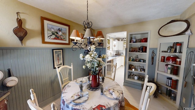 dining room with a textured ceiling, an inviting chandelier, and built in shelves