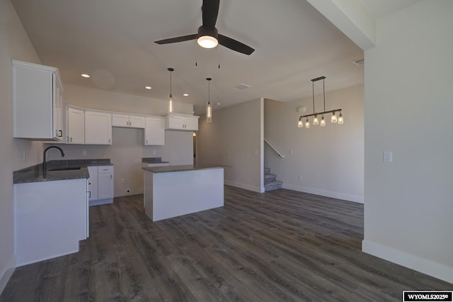 kitchen with a kitchen island, sink, white cabinets, ceiling fan, and dark wood-type flooring