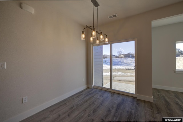 unfurnished dining area featuring a notable chandelier and dark wood-type flooring
