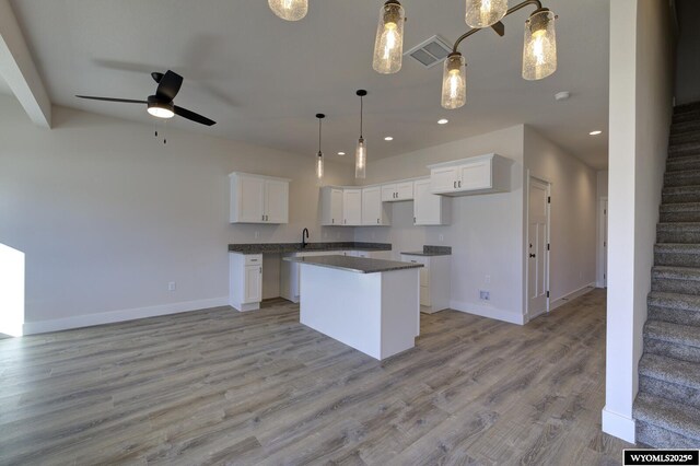 kitchen featuring sink, a center island, hanging light fixtures, light wood-type flooring, and white cabinets
