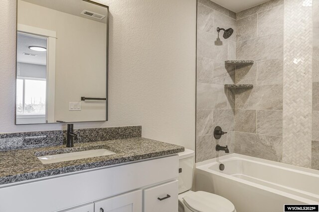 full bathroom featuring tiled shower / bath, vanity, and toilet