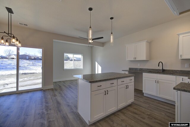 kitchen featuring sink, decorative light fixtures, a center island, dark hardwood / wood-style flooring, and white cabinets