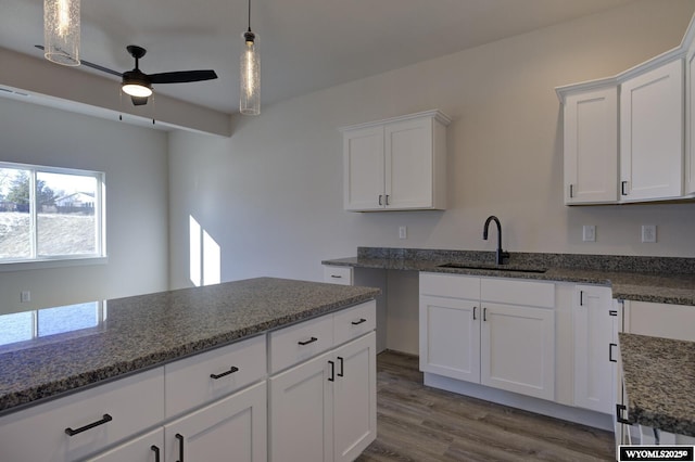 kitchen featuring dark stone countertops, sink, hanging light fixtures, and white cabinets