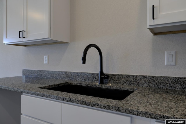 kitchen featuring white cabinetry, sink, and dark stone countertops