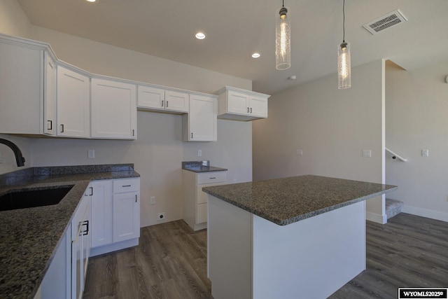 kitchen featuring dark hardwood / wood-style floors, sink, hanging light fixtures, and white cabinets