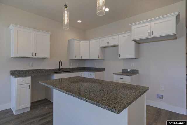 kitchen featuring hanging light fixtures, white cabinetry, a center island, and sink