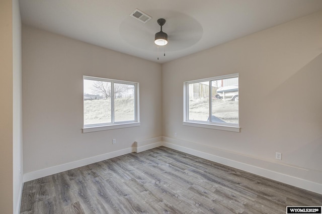 spare room with a wealth of natural light, ceiling fan, and light wood-type flooring