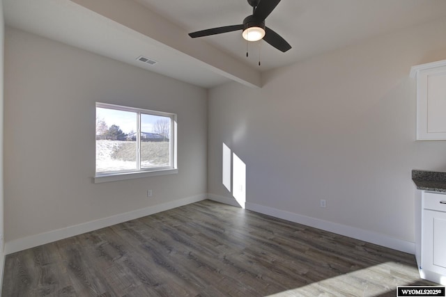 unfurnished living room featuring beam ceiling, dark hardwood / wood-style floors, and ceiling fan