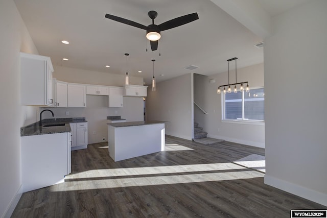 kitchen featuring sink, dark wood-type flooring, white cabinets, a kitchen island, and decorative light fixtures