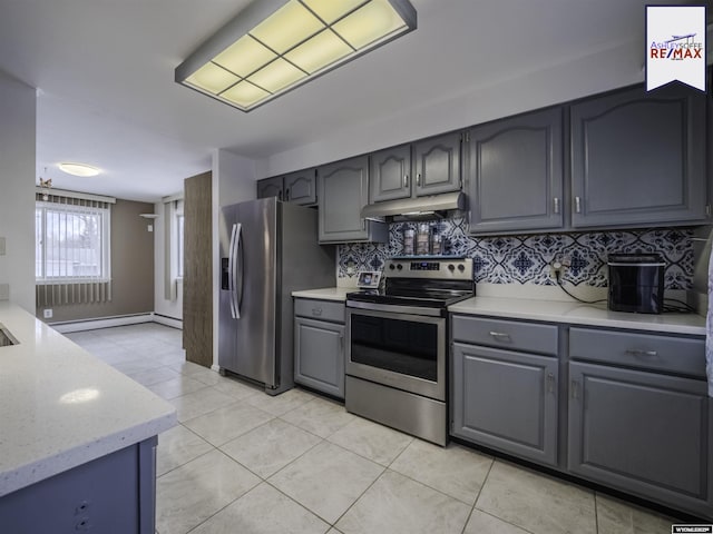 kitchen with appliances with stainless steel finishes, tasteful backsplash, gray cabinetry, light tile patterned floors, and baseboard heating