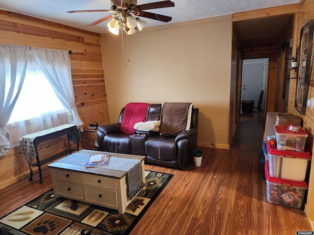 living room featuring ceiling fan, wooden walls, and light hardwood / wood-style floors