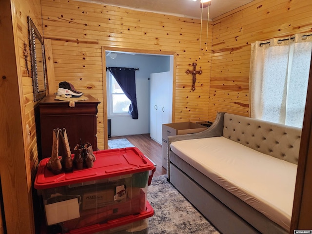 bedroom with hardwood / wood-style floors and wooden walls