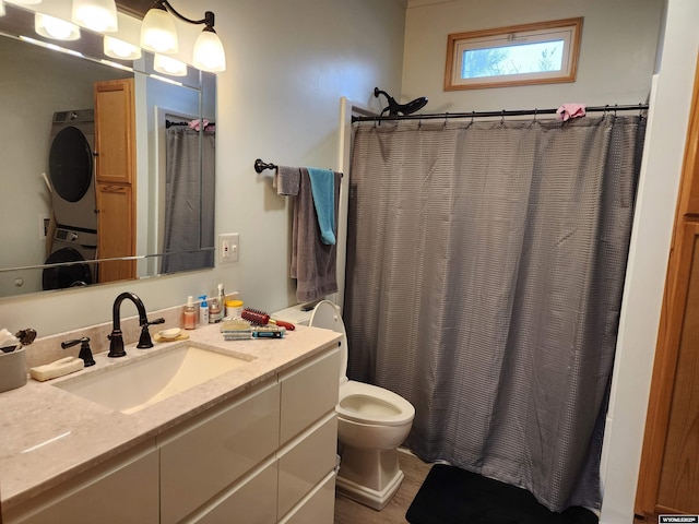 bathroom featuring stacked washer / drying machine, toilet, and vanity