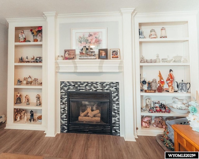 interior details featuring built in features, hardwood / wood-style floors, and a tile fireplace