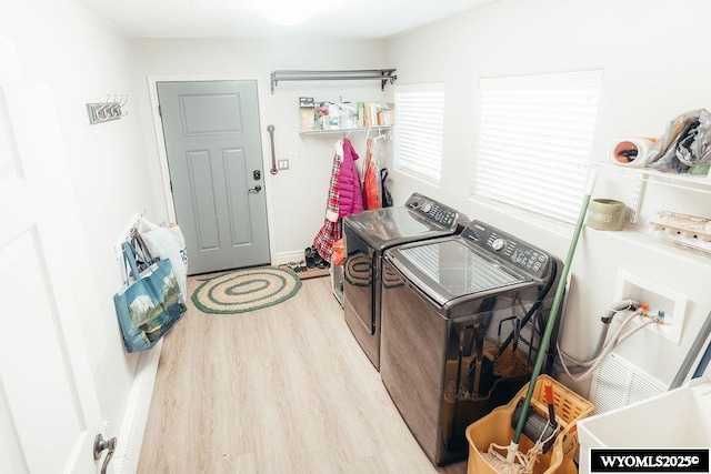 clothes washing area with light hardwood / wood-style floors and washer and dryer