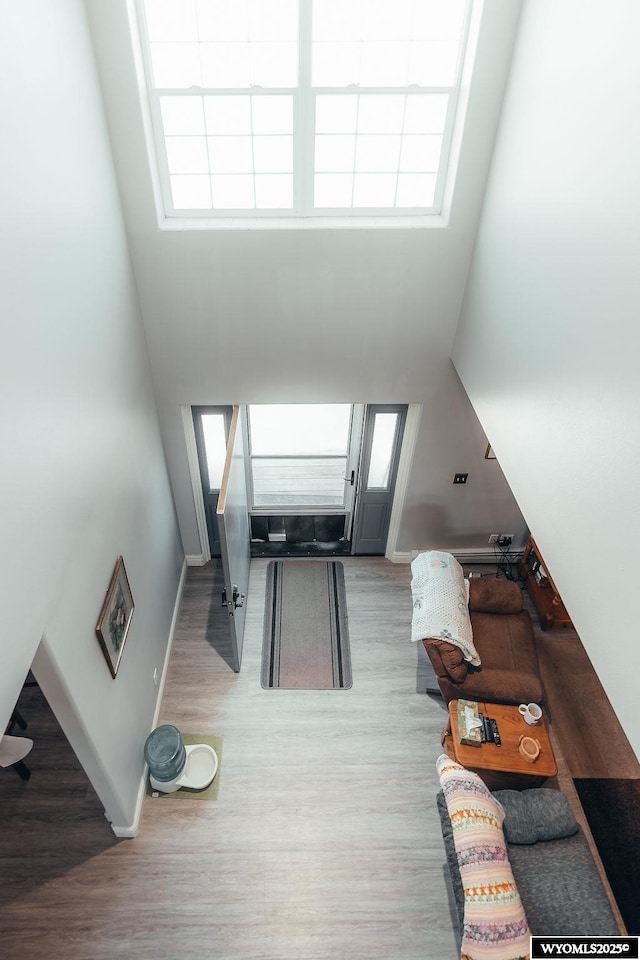 unfurnished living room with a towering ceiling, plenty of natural light, and light wood-type flooring