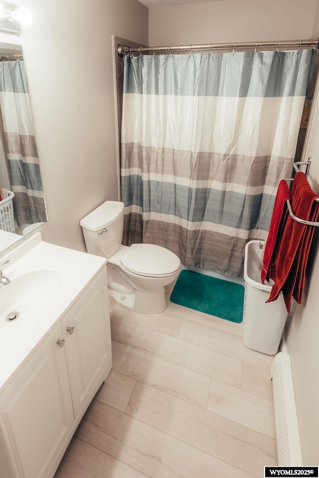 bathroom featuring vanity, walk in shower, toilet, and baseboard heating