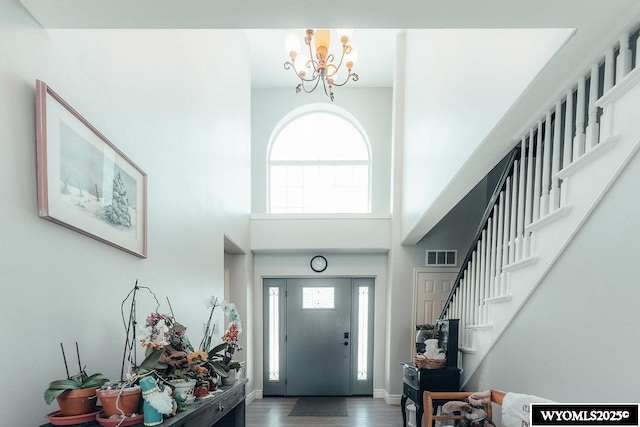 entrance foyer featuring an inviting chandelier, a towering ceiling, and hardwood / wood-style flooring