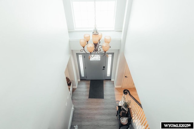 doorway to outside featuring a notable chandelier, wood-type flooring, and a high ceiling