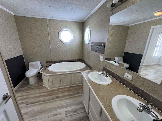 bathroom with toilet, a textured ceiling, ornamental molding, a bathtub, and hardwood / wood-style flooring