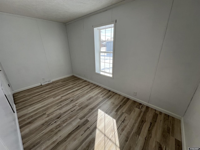 spare room featuring light hardwood / wood-style floors and a textured ceiling