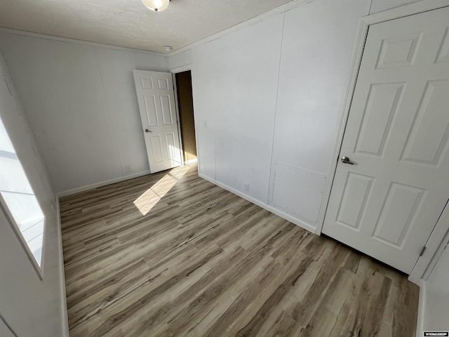 spare room with ornamental molding, a textured ceiling, and light hardwood / wood-style floors