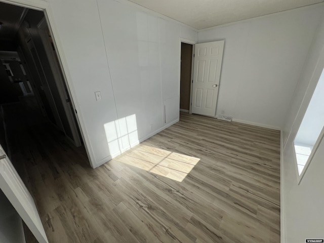 spare room with ornamental molding and light wood-type flooring