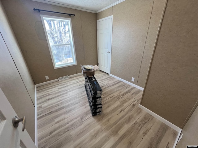 spare room featuring ornamental molding and light wood-type flooring