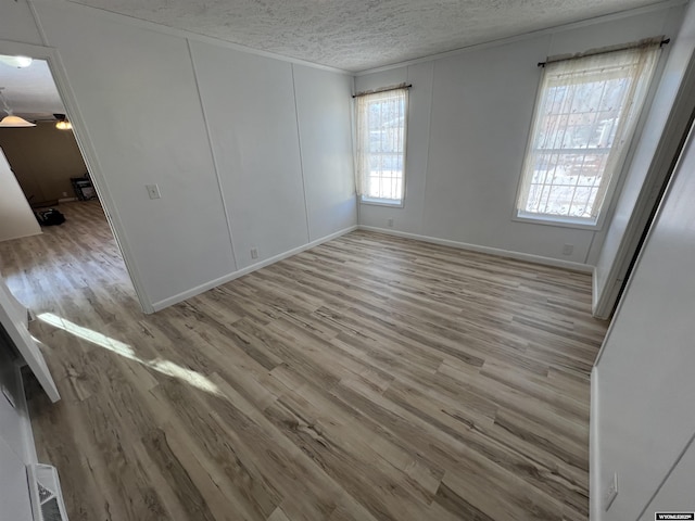 empty room with ceiling fan, a textured ceiling, and light hardwood / wood-style floors