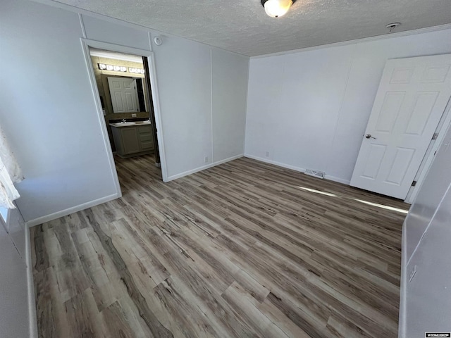 spare room with sink, wood-type flooring, and a textured ceiling