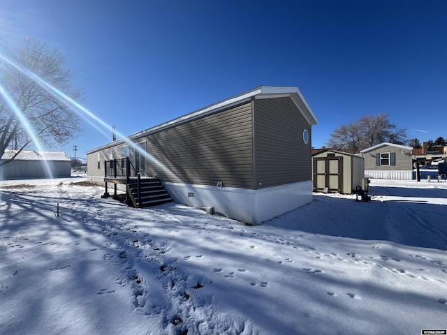 view of snowy exterior featuring a storage shed