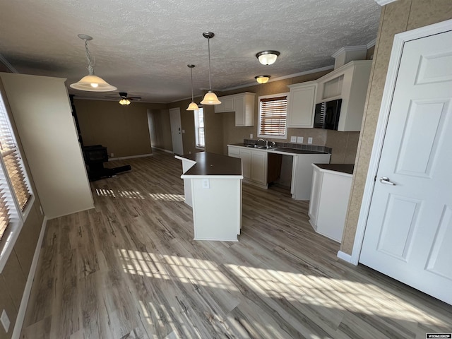 kitchen with crown molding, hanging light fixtures, light hardwood / wood-style floors, white cabinets, and a kitchen island