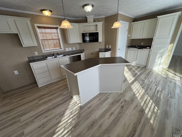 kitchen with sink, decorative light fixtures, white cabinets, and a kitchen island