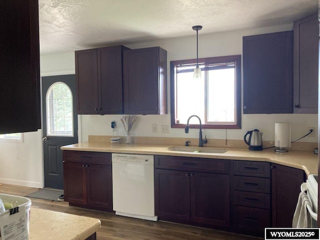 kitchen featuring pendant lighting, dishwasher, sink, dark wood-type flooring, and a textured ceiling