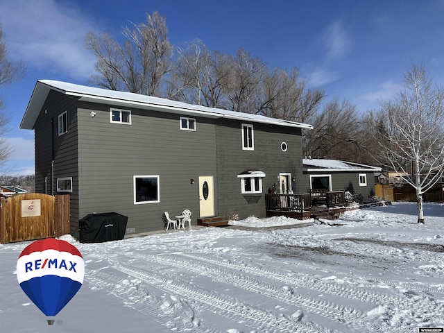 snow covered back of property with a deck