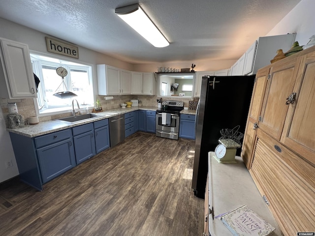 kitchen featuring blue cabinetry, sink, white cabinetry, appliances with stainless steel finishes, and decorative backsplash