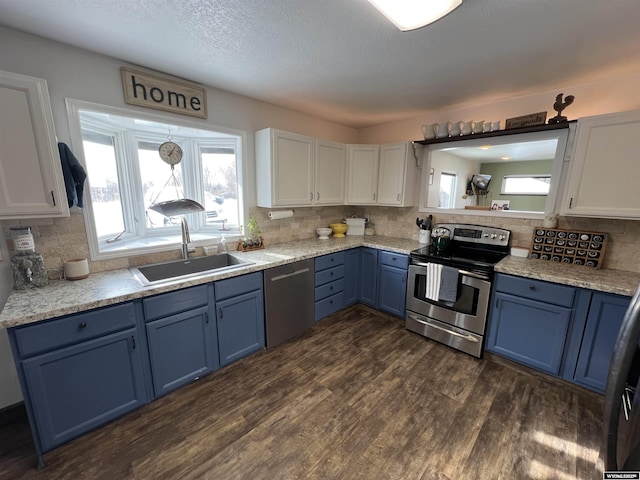 kitchen with appliances with stainless steel finishes, sink, white cabinets, dark wood-type flooring, and blue cabinetry