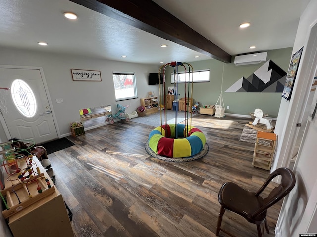 playroom featuring wood-type flooring, beam ceiling, and an AC wall unit