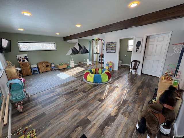 recreation room featuring beam ceiling, a wealth of natural light, and dark wood-type flooring