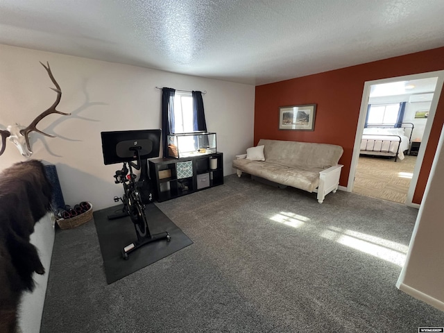 exercise area with a healthy amount of sunlight, a textured ceiling, and dark carpet