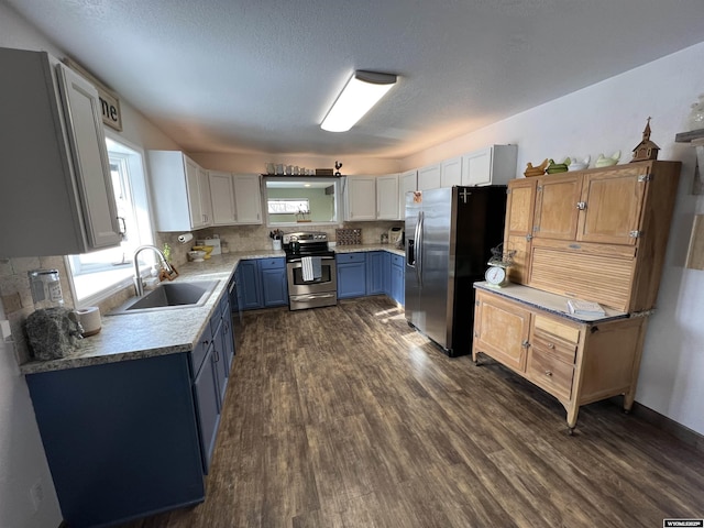 kitchen featuring dark wood-type flooring, blue cabinetry, sink, stainless steel appliances, and decorative backsplash