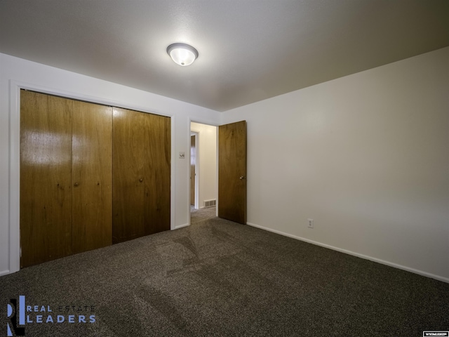 unfurnished bedroom with a closet and dark colored carpet