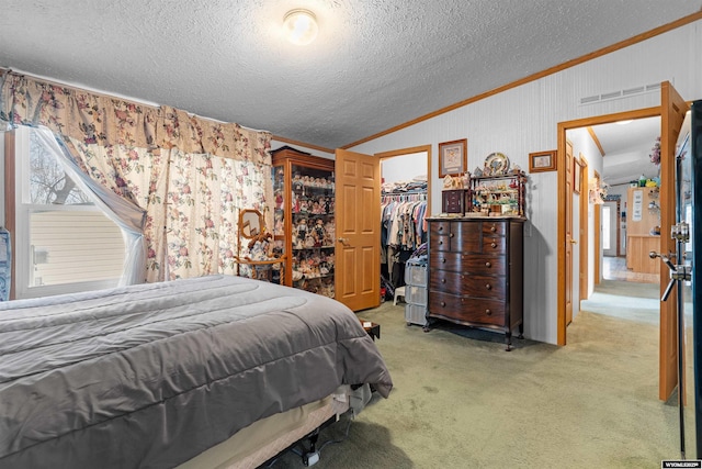 carpeted bedroom featuring lofted ceiling, crown molding, a textured ceiling, a spacious closet, and a closet