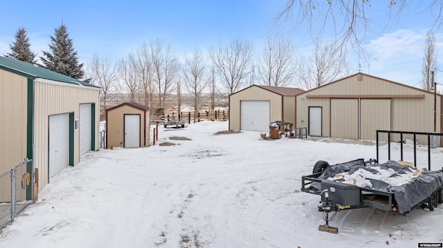 yard layered in snow featuring a garage and an outdoor structure