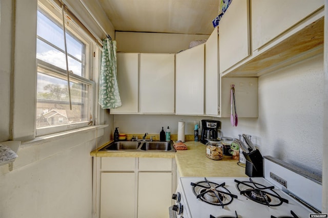 kitchen featuring sink, white gas range oven, and white cabinets