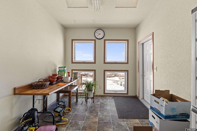 entryway with baseboards, a textured ceiling, and a textured wall