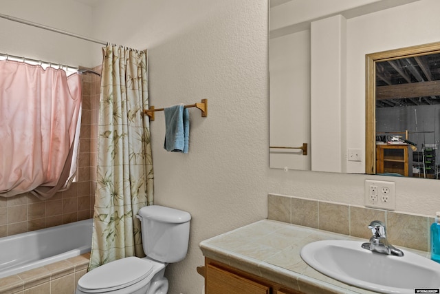 full bathroom featuring vanity, toilet, a textured wall, and tiled shower / bath combo