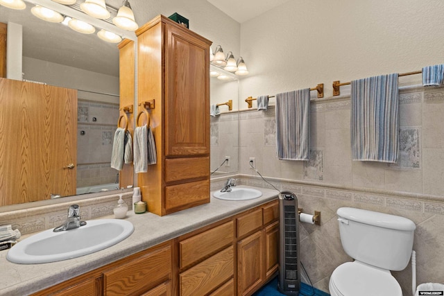 full bath featuring tile walls, toilet, double vanity, and a sink