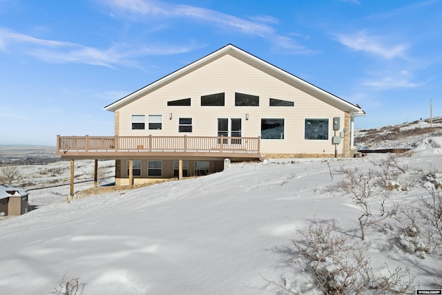 snow covered back of property with a deck