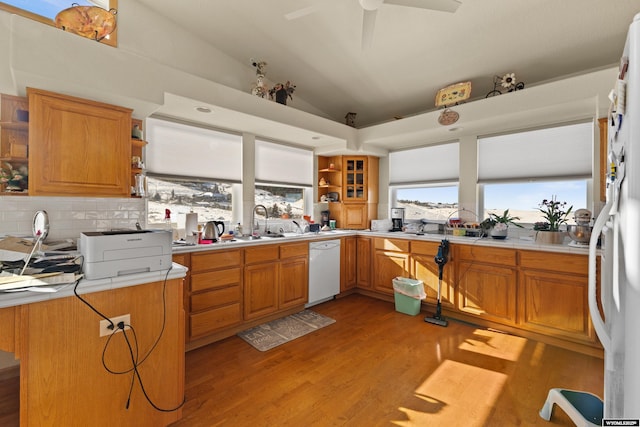 kitchen with lofted ceiling, sink, light wood-type flooring, dishwasher, and backsplash